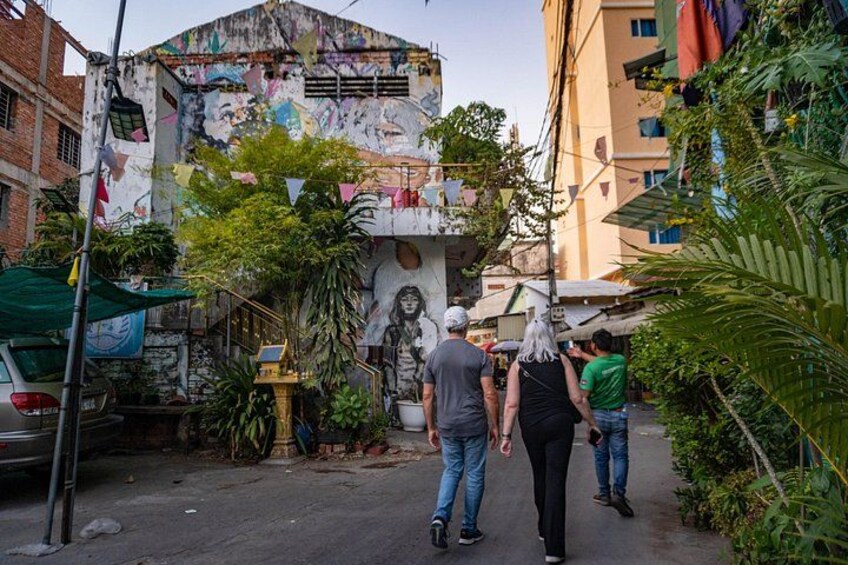 A street with a mural, a parked car, and a person walking. 3
