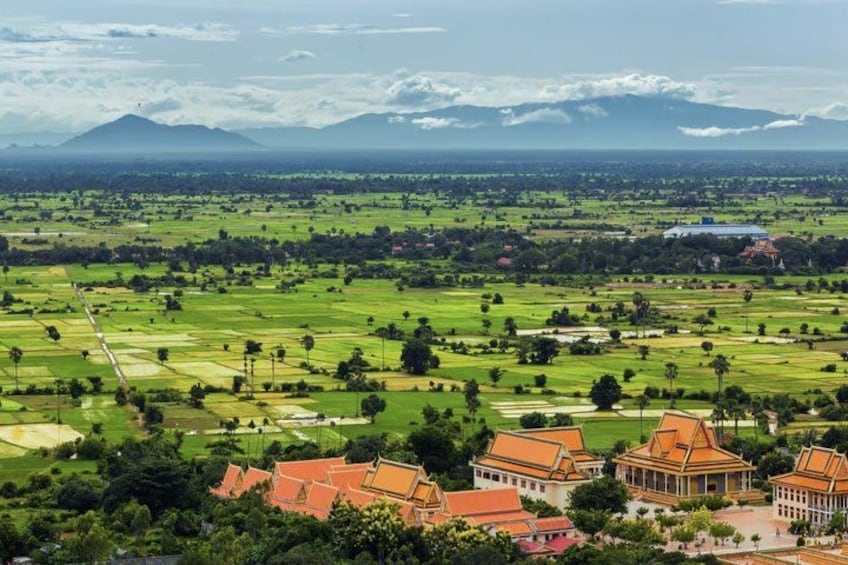 Un paisaje con campos de cultivo, un complejo de templos y montañas lejanas. 4