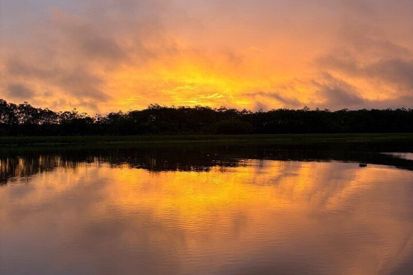 A sunset over a calm lake with reflections of the sky. 1