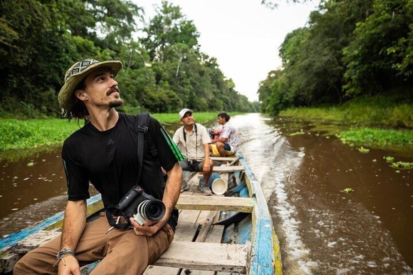 A river with a wooden boat carrying three people. 1