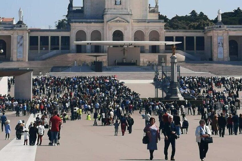 A large crowd in a public square with a prominent building in the background. 2