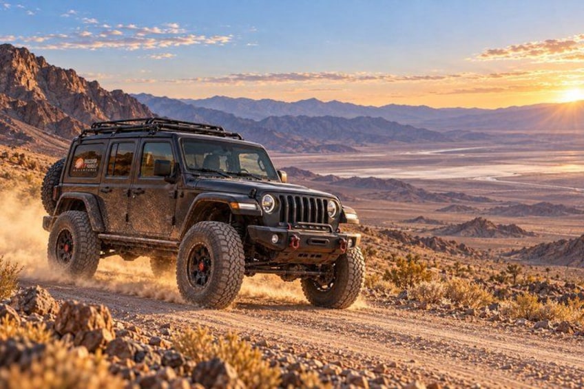 A black off-road vehicle on a dirt road with a mountainous landscape in the background. 1