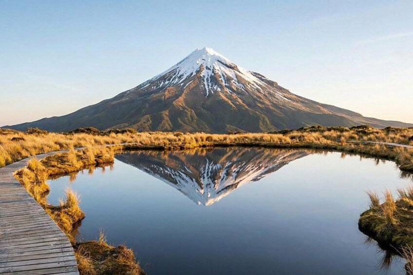 A snow-capped mountain, a calm lake, and a wooden boardwalk. 5