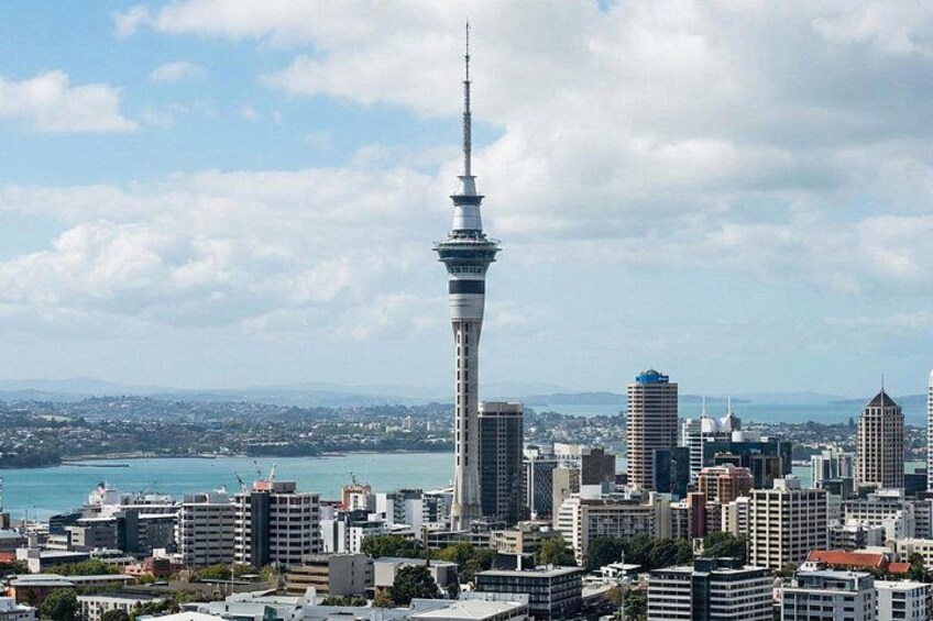 A cityscape with a prominent tower, various buildings, and a body of water in the background. 4