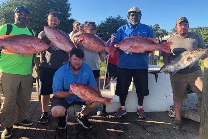 Un grupo de personas sosteniendo peces grandes sobre una cubierta de madera. 2