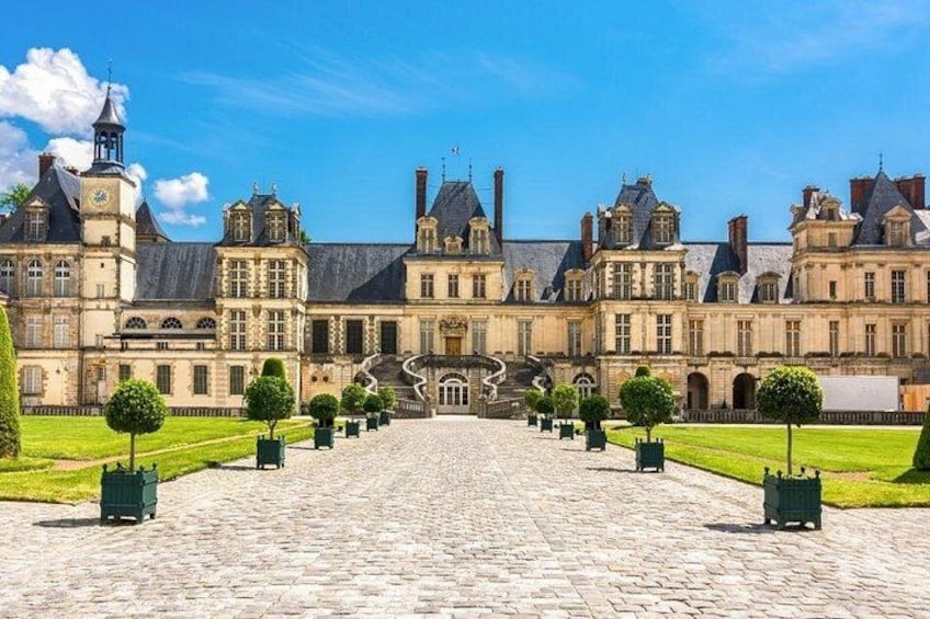 A historic building with a symmetrical facade, a central staircase, and a cobblestone courtyard. 2