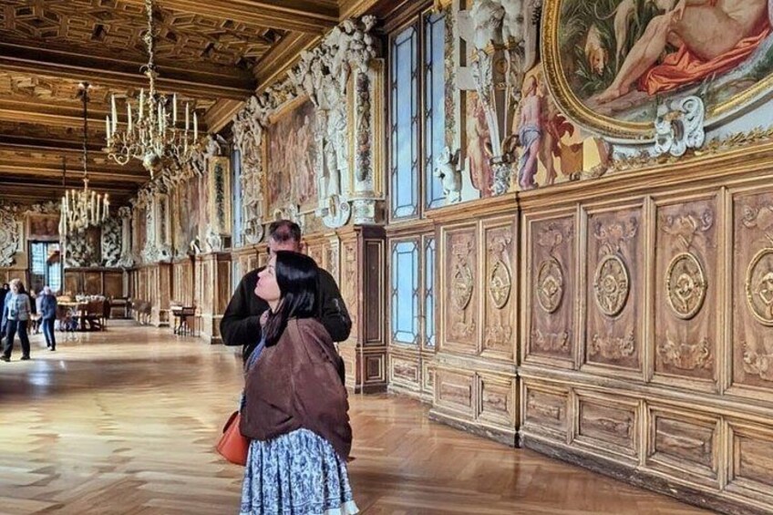An ornate hall with high ceilings, detailed wood paneling, and classical artwork. 5