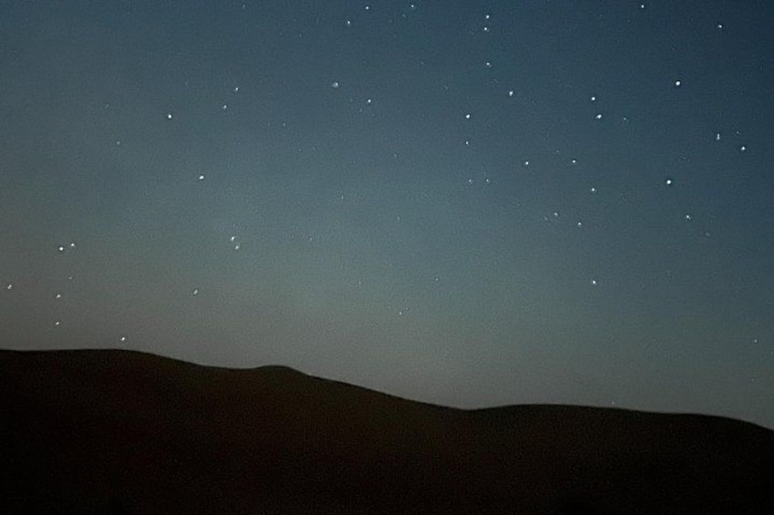 A night sky with stars and silhouettes of hills. 1