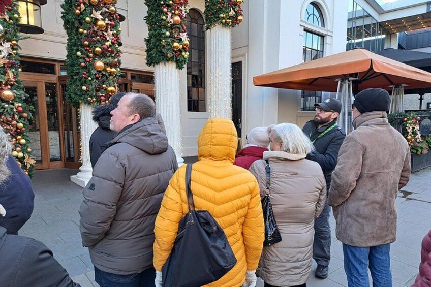 People standing outside a building with Christmas decorations. 2
