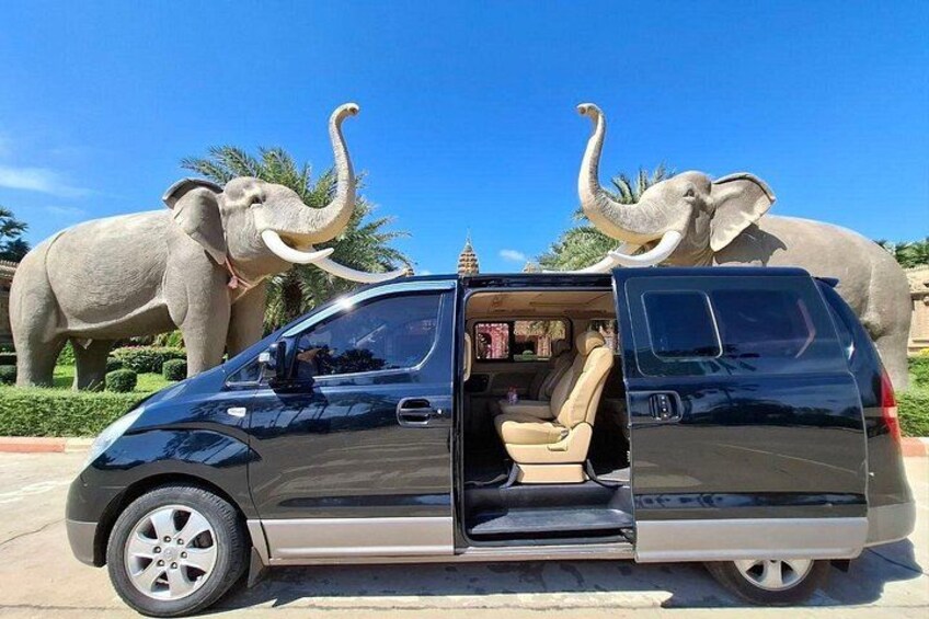 Una camioneta negra estacionada con la puerta abierta, rodeada por dos estatuas de elefantes. 5