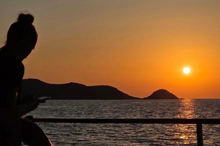 A silhouette of a person reading a book by a body of water during sunset. 2