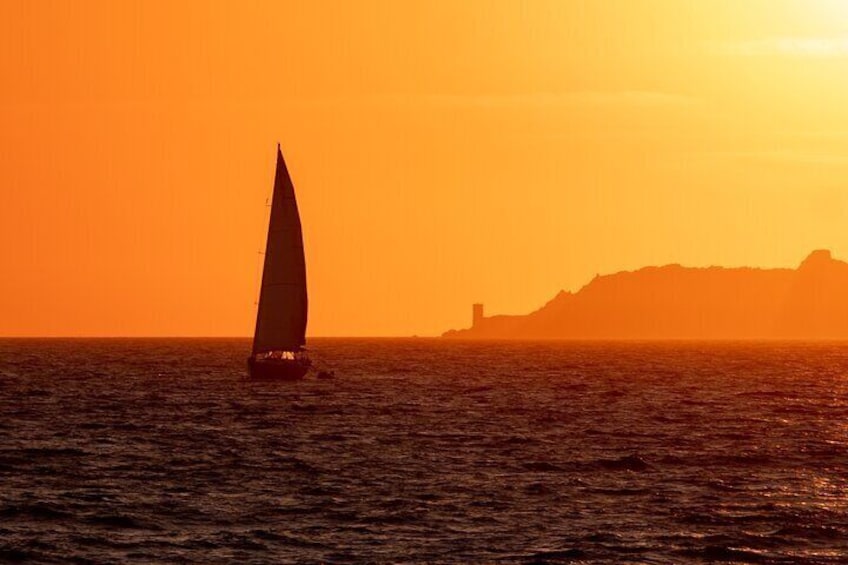 A sailboat on the ocean during sunset with a distant mountain and lighthouse. 4