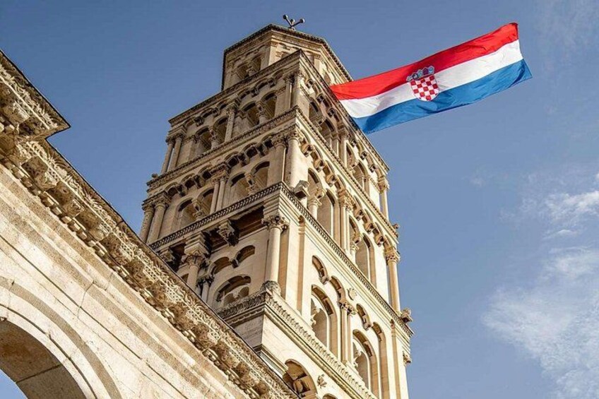Ein historisches Gebäude mit einem Glockenturm, an dem die kroatische Flagge weht. 5
