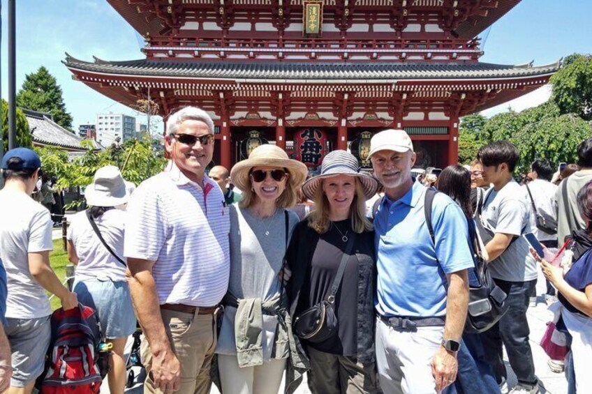 A group of people standing in front of a traditional red pagoda with a tiled roof. 5