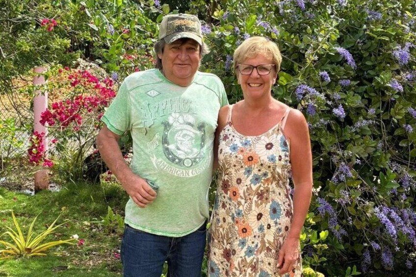 Un uomo e una donna in un giardino con piante fiorite e una recinzione. 4