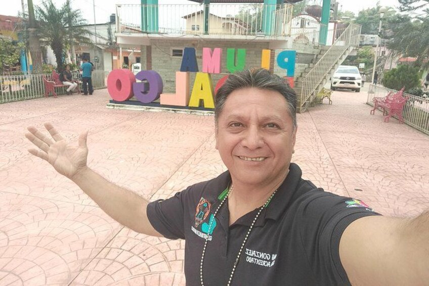 A person taking a selfie with a colorful sign in the background. 5