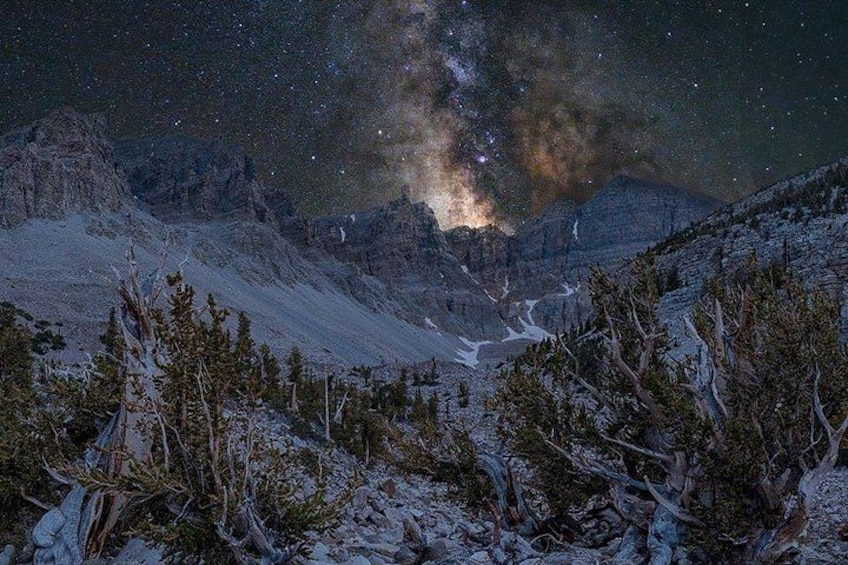 A snowy mountain landscape at night with a starry sky and the Milky Way visible. 2
