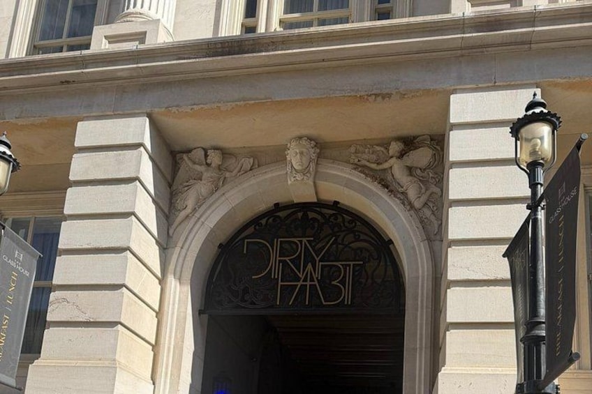 A building entrance with an ornate archway and a sign that reads 'DRINK FAST.' 4