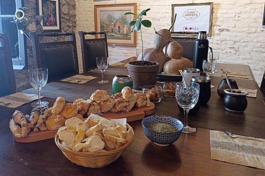 A wooden table with various food items, a basket of bread, a bowl of spices, and a sign that reads 'Casa Abierta.' 1