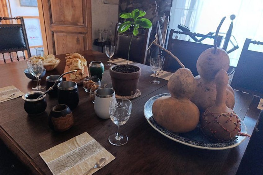 A wooden dining table with various food items, drinks, and decorative objects. 4