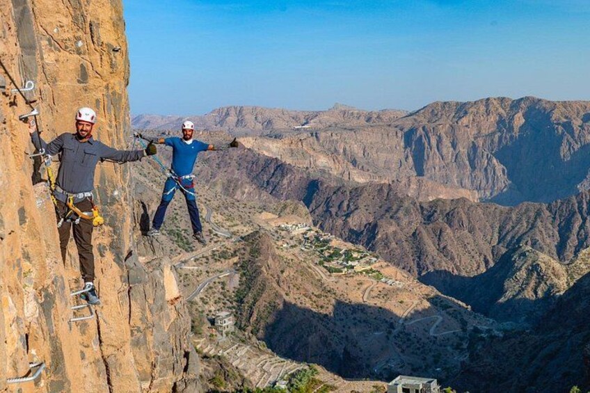 Two climbers on a steep rock face with a vast canyon in the background. 3