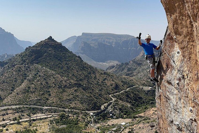 A person rock climbing on a steep cliff with a mountainous landscape in the background. 4