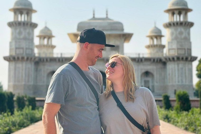 A couple standing in front of a large, historic building with domes and minarets. 1