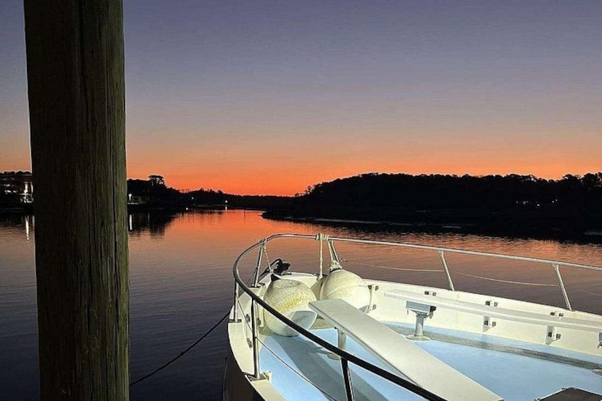 A boat docked at a pier with a sunset in the background. 1