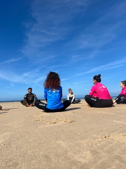 A group of people sitting on a beach facing the ocean. 5