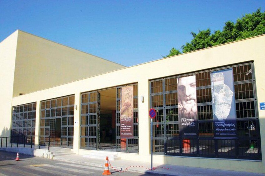 A modern building with large windows and banners advertising an exhibition. 3
