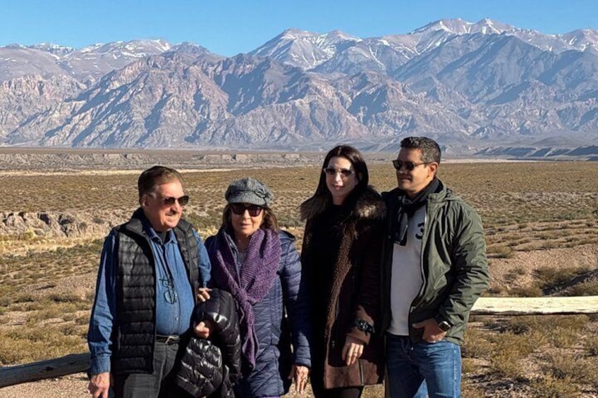 A group of people standing in a barren landscape with mountains in the background. 3