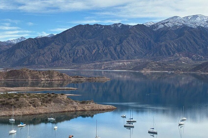 A calm lake with boats, mountains, and a clear sky. 5