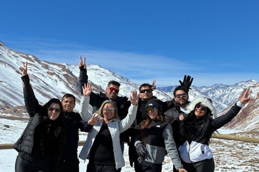 A group of people posing on a snow-covered mountain with clear skies. 1