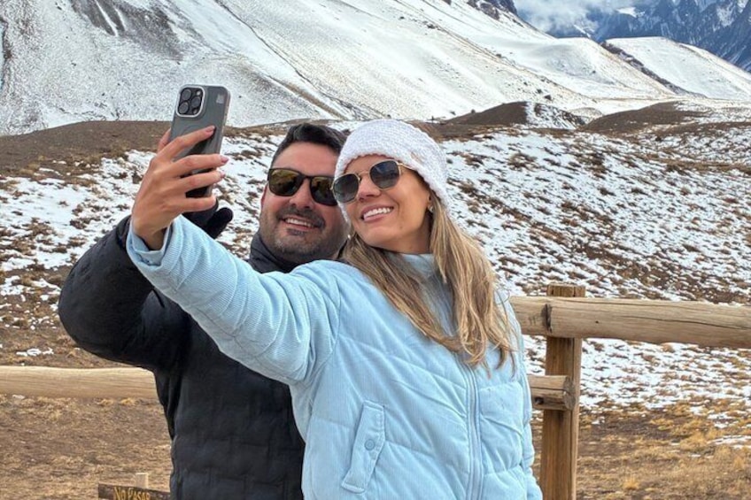 Two people taking a selfie with a mountainous landscape in the background. 2