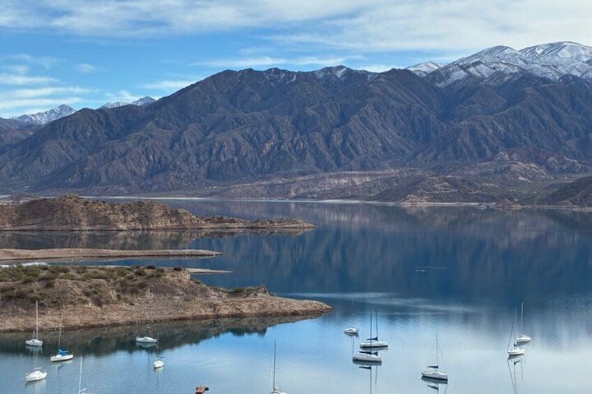 A calm lake with boats, mountains, and snow-capped peaks in the background. 5