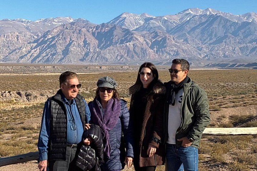 A group of four people standing in a desert landscape with mountains in the background. 3