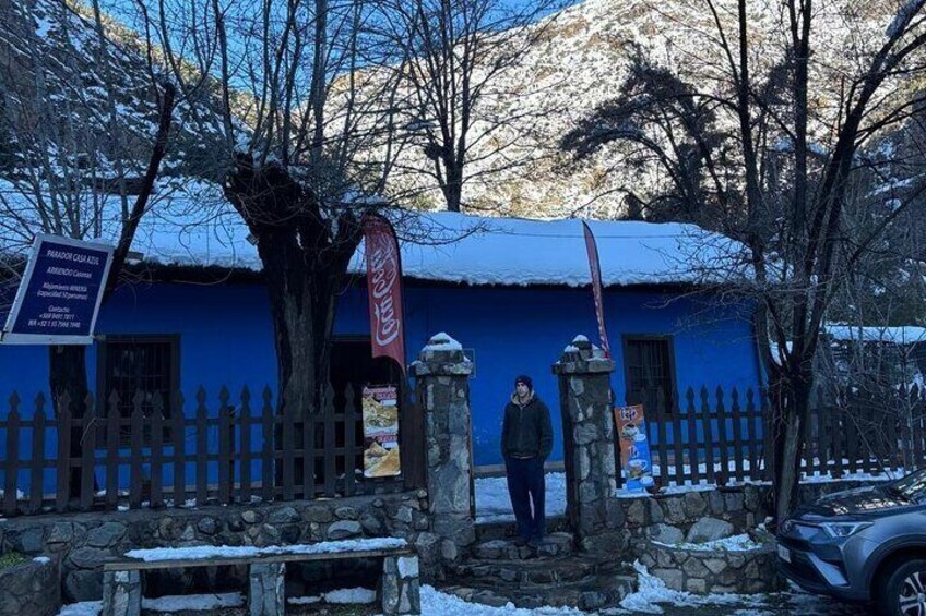 A blue building with a stone fence, a Coca-Cola sign, and a person standing in front. 1