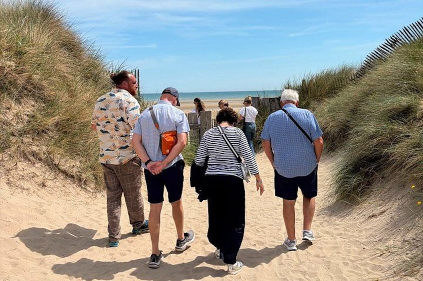 A group of people walking on a sandy path with dunes on either side. 4