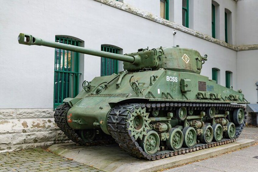 A green armored tank with the label 'BOSS' parked in front of a building with green windows. 4