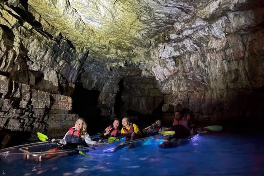 People kayaking in a cave with rocky walls and a pool of water. 2