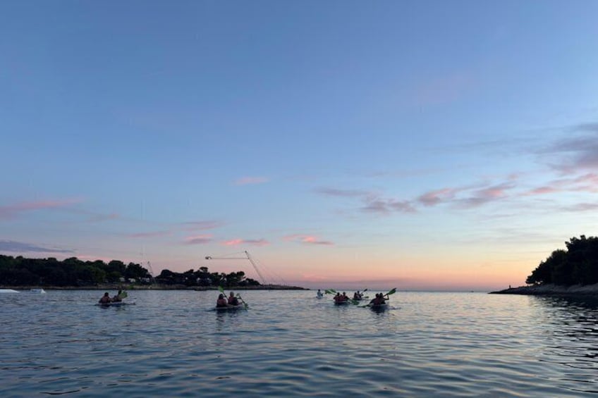 A calm body of water with several small boats and people engaged in water activities. 5
