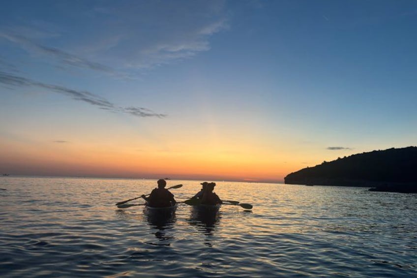Two people kayaking on calm water during sunset. 4