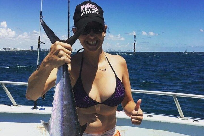 A person holding a fish on a boat with a city skyline in the background. 4