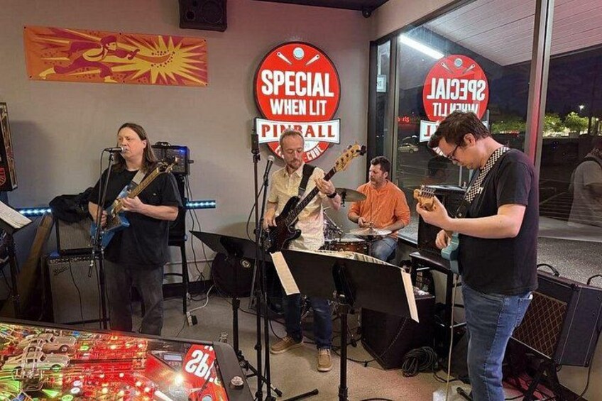 Una banda actuando en una sala con instrumentos musicales y un cartel que dice 'SPECIAL WHEN IT'S RAINY'. 2