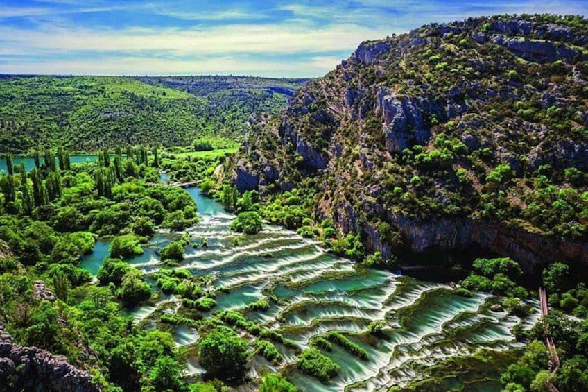 A river with terraced fields, lush greenery, and rocky cliffs. 3