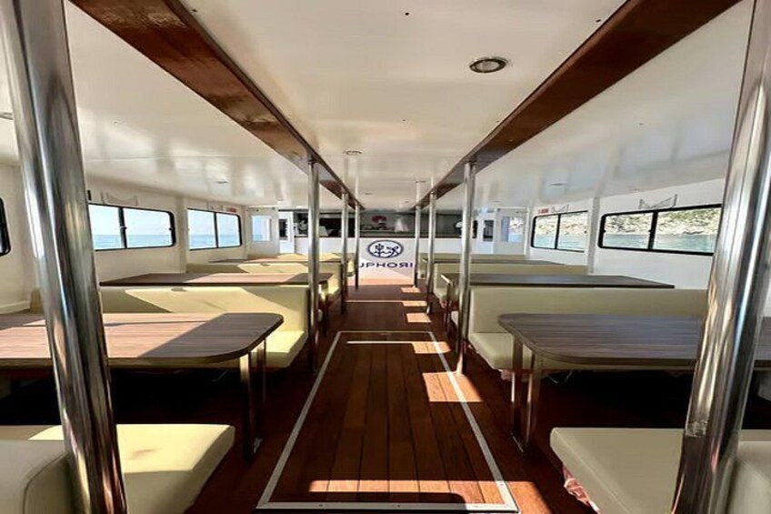 A boat interior with wooden flooring, white walls, and windows. 2