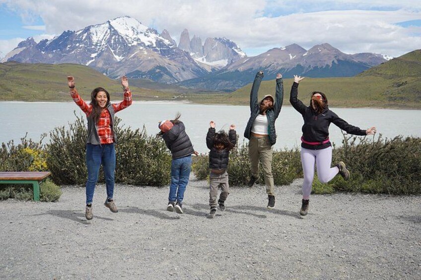 A group of people jumping in front of a lake with mountains in the background. 5