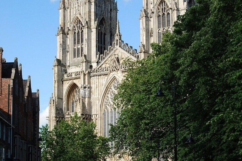 A historic cathedral with intricate Gothic architecture, surrounded by lush green trees. 1