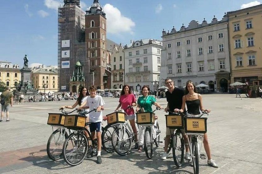 A group of people on bicycles in a public square with historic buildings in the background. 5