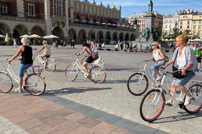 People riding bicycles in a public square with historic architecture. 3